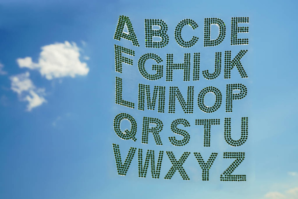 Set - the English alphabet from green rhinestones on blue sky background.  - Zdjęcie, obraz
