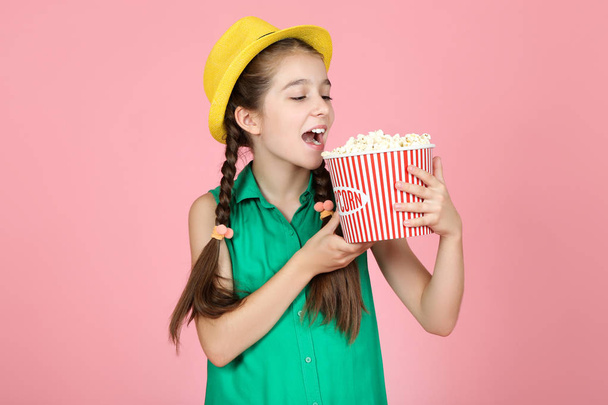Beautiful young girl holding bucket with popcorn on pink backgro - Fotoğraf, Görsel