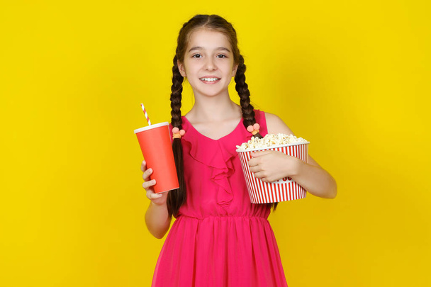Beautiful young girl holding bucket with popcorn and paper cup o - Fotoğraf, Görsel