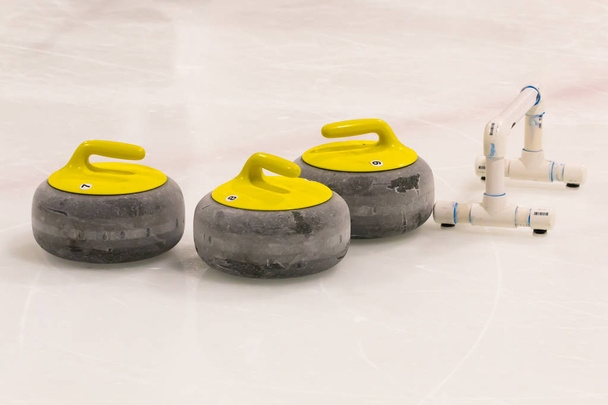 Skupina žlutých curlingových kamenů se stabilizační tyčí pro trénink.  - Fotografie, Obrázek