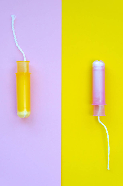 zwei Hygiene-Tampons mit Applikator auf rosa und gelbem Hintergrund. zuverlässiger Schutz während der Menstruation. Kopierraum. Ansicht von oben. flache Lage - Foto, Bild
