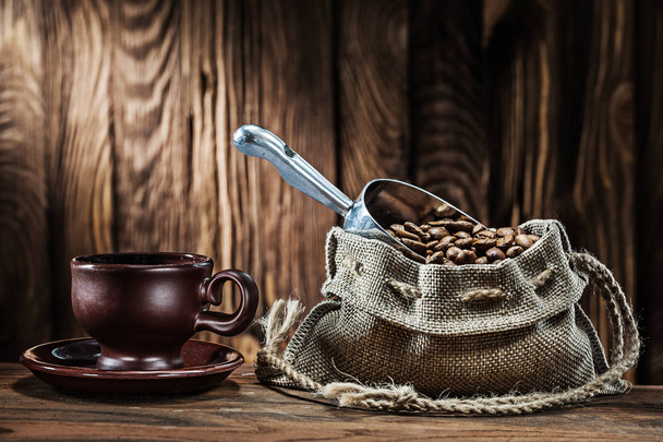 old brown clay coffee cup and sack with beans on vintage wooden  - Photo, image