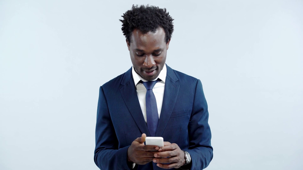lächelnder afrikanisch-amerikanischer Geschäftsmann mit Smartphone isoliert auf grau - Filmmaterial, Video