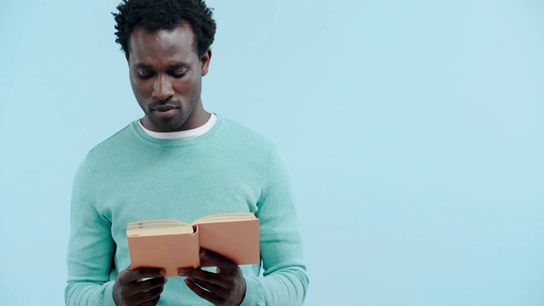улыбающийся африканский американец читает книгу, изолированную на голубом
 - Кадры, видео
