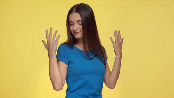happy girl gesturing and dancing isolated on yellow - Materiał filmowy, wideo