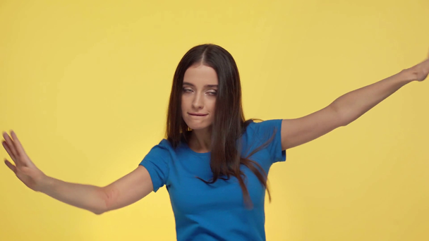 mooi meisje wijzend met vingers en dansen geïsoleerd op geel - Video