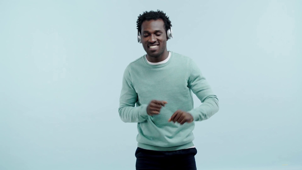 dromerig Afrikaans amerikaanse man dansen in koptelefoon geïsoleerd op blauw - Video