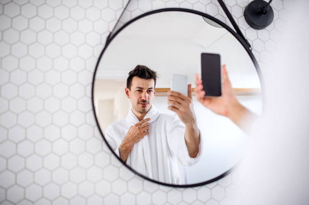 Young man with smartphone in the bathroom in the morning, taking selfie. - Fotó, kép