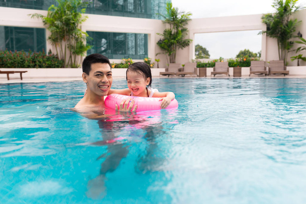 Happy family in swimming pool. Summer holidays and vacation concept - Фото, изображение