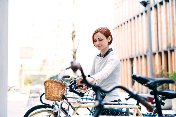 A young business woman with bicycle standing outdoors. - Photo, Image