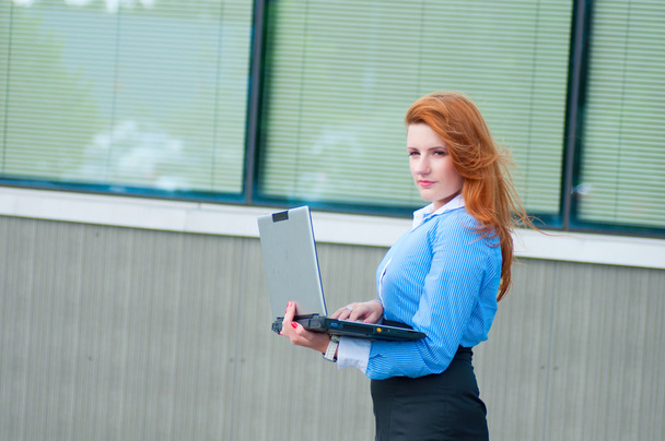 Business woman posing with a laptop in a front of office building - Foto, Bild