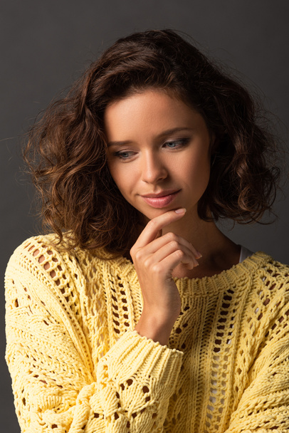 dreamy curly woman in yellow knitted sweater on black background - Photo, Image