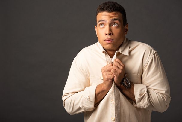 handsome mixed race man in beige shirt feeling cold on black background - Photo, Image
