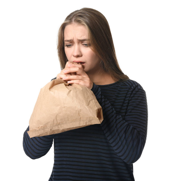 Woman with paper bag having panic attack on white background - Photo, Image