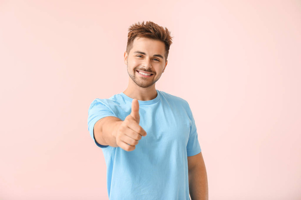 Muotokuva onnellinen nuori mies osoittaa peukalo-up ele väri tausta
 - Valokuva, kuva