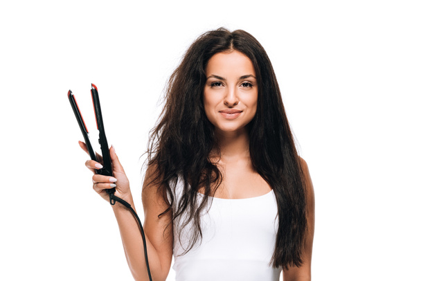 smiling brunette beautiful woman with straight and curly hair holding flat iron  isolated on white - Φωτογραφία, εικόνα