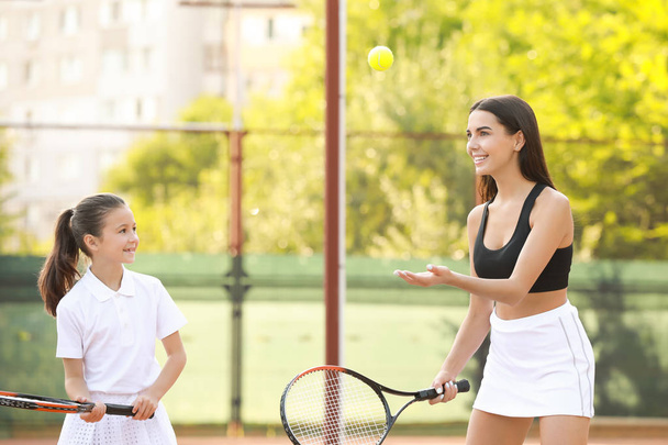 Petite fille et sa mère jouant au tennis sur le court
 - Photo, image
