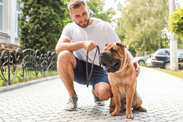 Sporty man with cute dog walking outdoors - Zdjęcie, obraz