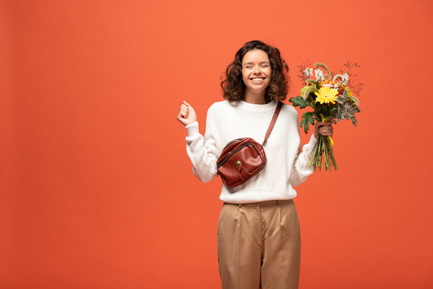 femme heureuse en tenue automnale tenant bouquet de fleurs isolé sur orange
 - Photo, image