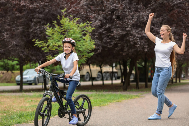 Matka dumna ze swojej córki, która nauczył się jeździć na rowerze na zewnątrz - Zdjęcie, obraz