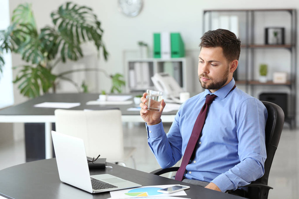 Portrait of businessman drinking water in office - Photo, image