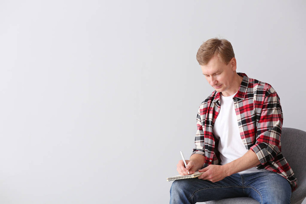 Portrait of handsome man with notebook on light background - Photo, Image