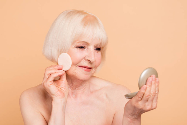 Close-up portrait of her she nice-looking attractive nude naked well-groomed peaceful gray-haired lady holding in hands mirror beauty time removing make-up isolated over beige background - Fotó, kép