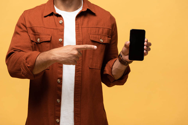 cropped view of mixed race man pointing with finger at smartphone with blank screen isolated on yellow - Foto, Imagem