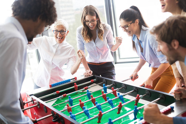 Business people having great time together. Colleagues playing table football in office - Photo, Image