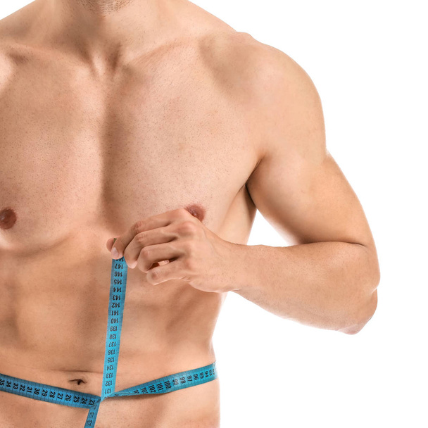 Handsome muscular man with measuring tape on white background. Weight loss concept - 写真・画像