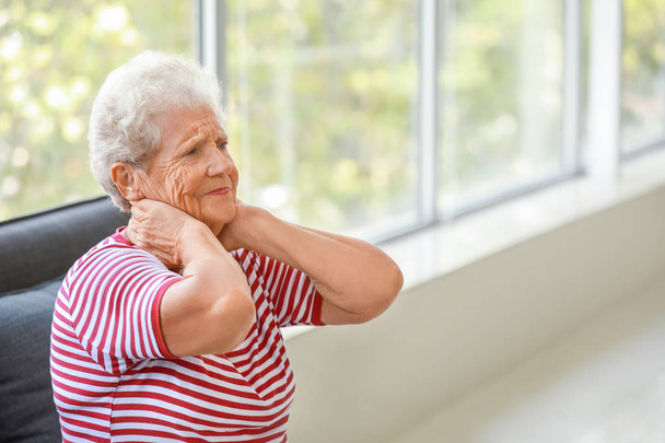 Vanhempi nainen, joka kärsii kaulasta kotona
 - Valokuva, kuva