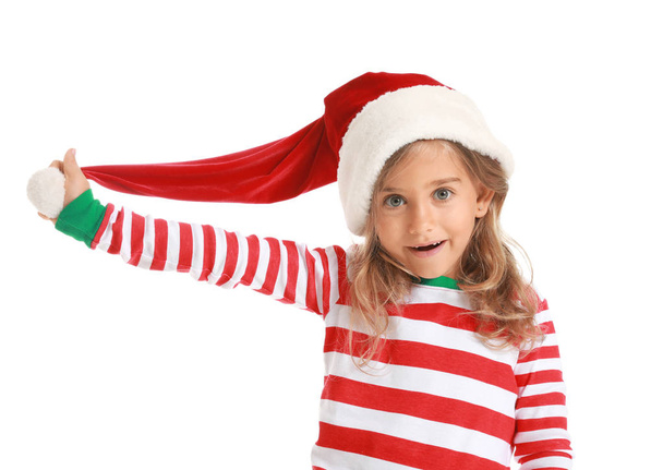Verrast klein meisje in pyjama en kerstman hoed op witte achtergrond - Foto, afbeelding