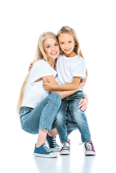 happy mother and daughter hugging and looking at camera on white - Фото, изображение