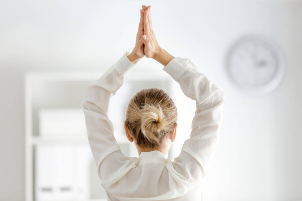 Jeune femme d'affaires pratiquant le yoga au bureau, vue de dos
 - Photo, image