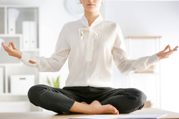 Молода бізнес-леді медитує в офісі
 - Фото, зображення