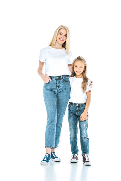happy woman standing with hand in pocket near kid on white  - Фото, зображення