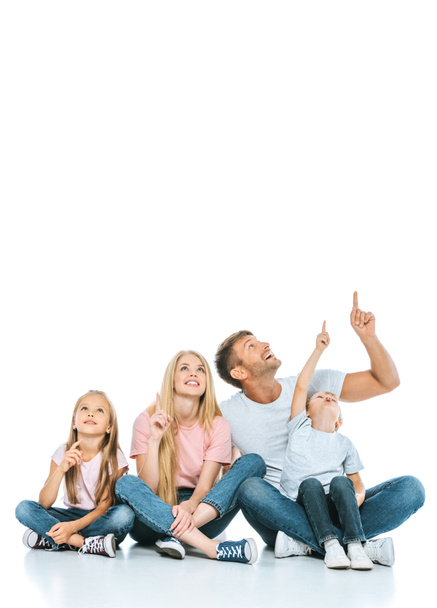 glückliche Familie, die mit den Fingern zeigt, während sie auf weiß schaut  - Foto, Bild