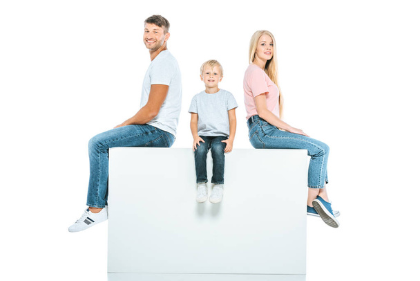 happy parents and son sitting on cube isolated on white  - Photo, Image