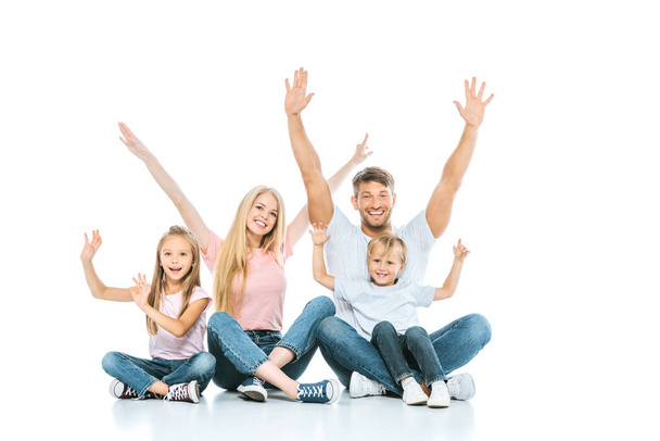 ευτυχισμένη οικογένεια με τα χέρια πάνω από τα κεφάλια χαμογελώντας στα λευκά  - Φωτογραφία, εικόνα