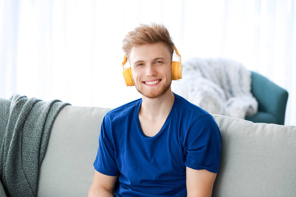 Komea nuori mies kuuntelemassa musiikkia kotona - Valokuva, kuva