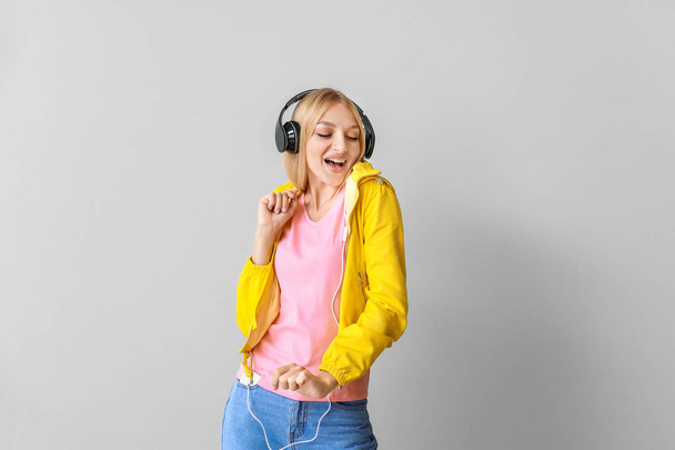 Szép fiatal nő zenét hallgat világos háttér - Fotó, kép