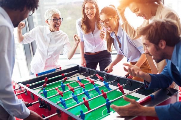 Business people having great time together. Colleagues playing table football in office - Foto, afbeelding