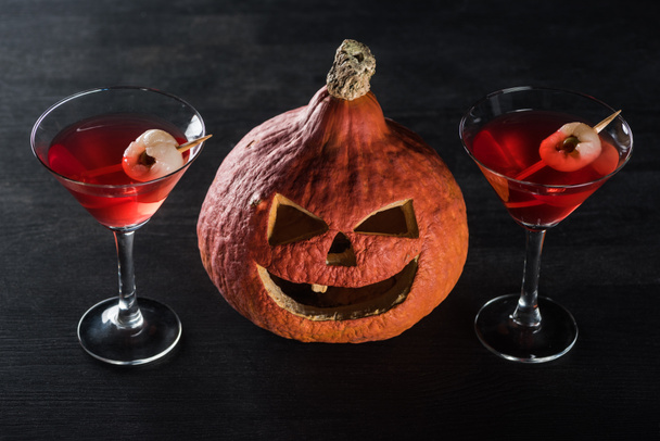 spooky Halloween pumpkin and red cocktails on black background - Φωτογραφία, εικόνα