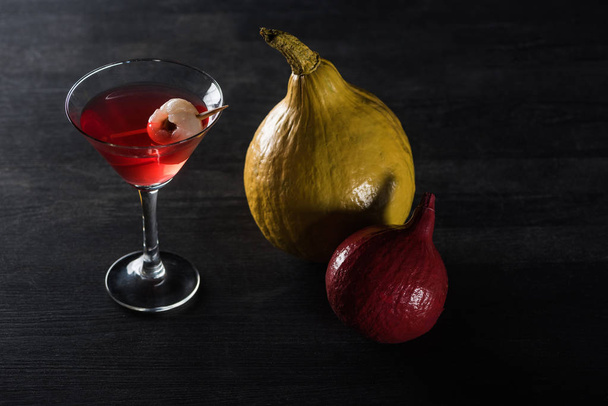 ripe pumpkins and red cocktail on black background - Foto, afbeelding
