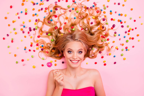 Close up top above high angle view photo beautiful glad she her lady lying down sweets ideal hair colored little candies trying lollypop wearing classy chic dress isolated pink background - Photo, image