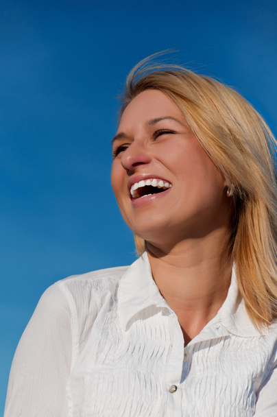 Beautiful woman smiling portait in white shirt over blue sky - Photo, image