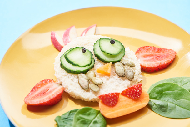 vista de cerca del plato con la cara de lujo hecha de comida para niños desayuno sobre fondo azul
 - Foto, Imagen
