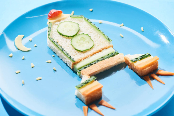 青い背景に子供の朝食のための食べ物で作られたロケットでプレートのクローズアップビュー - 写真・画像
