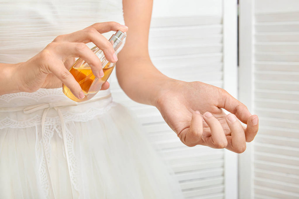 Beautiful young bride with bottle of perfume at home, closeup - Φωτογραφία, εικόνα