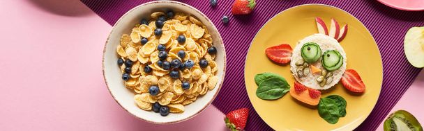 Widok z góry na płyty z fantazyjną krową z jedzenia w pobliżu owoców i płatków śniadaniowych na fioletowym tle - Zdjęcie, obraz